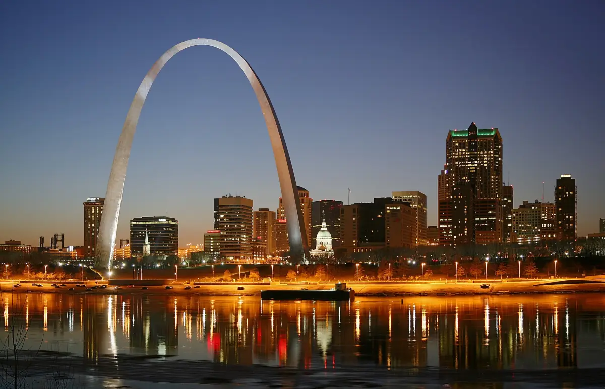 Gateway Arch and the St. Louis skyline glowing at dusk with river reflections