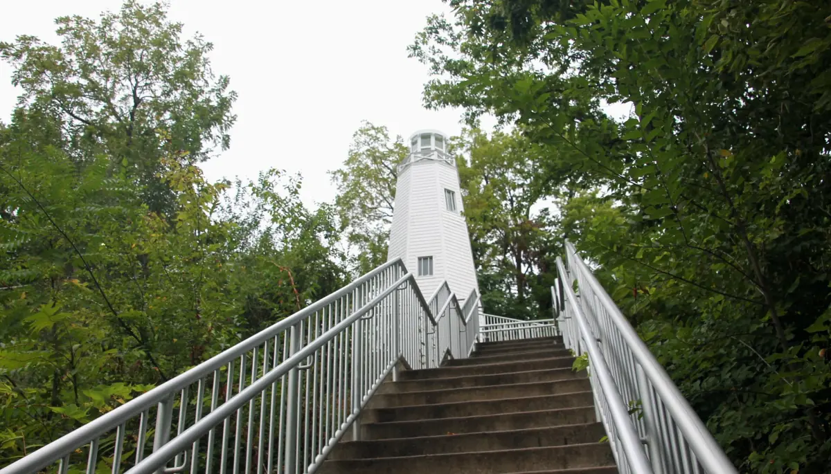 Stairs leading up to the white Mark Twain Memorial Lighthouse among trees in Hannibal