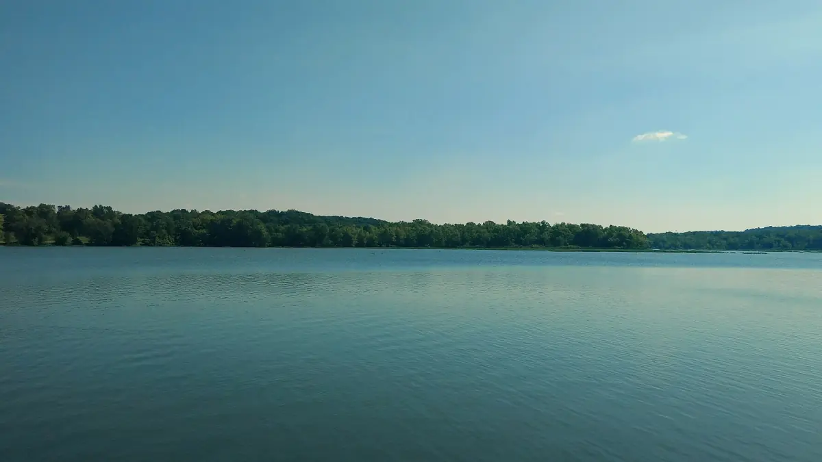 Calm blue water of Lake Springfield with a tree-lined shore under a clear sky