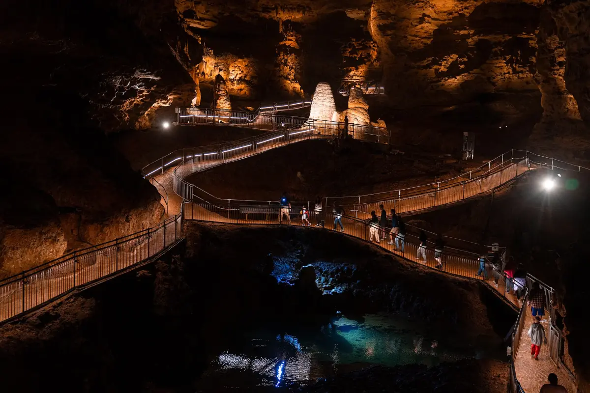 Beleuchteter Besucherweg windet sich über dunklem Wasser zwischen Felswänden in der Onondaga Cave